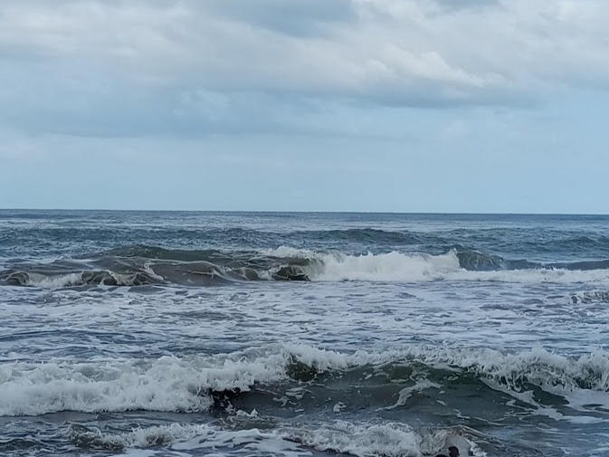 Onde agitate dell'oceano sotto un cielo nuvoloso in Costa Rica, simbolo dell’energia selvaggia della Pura vida.
