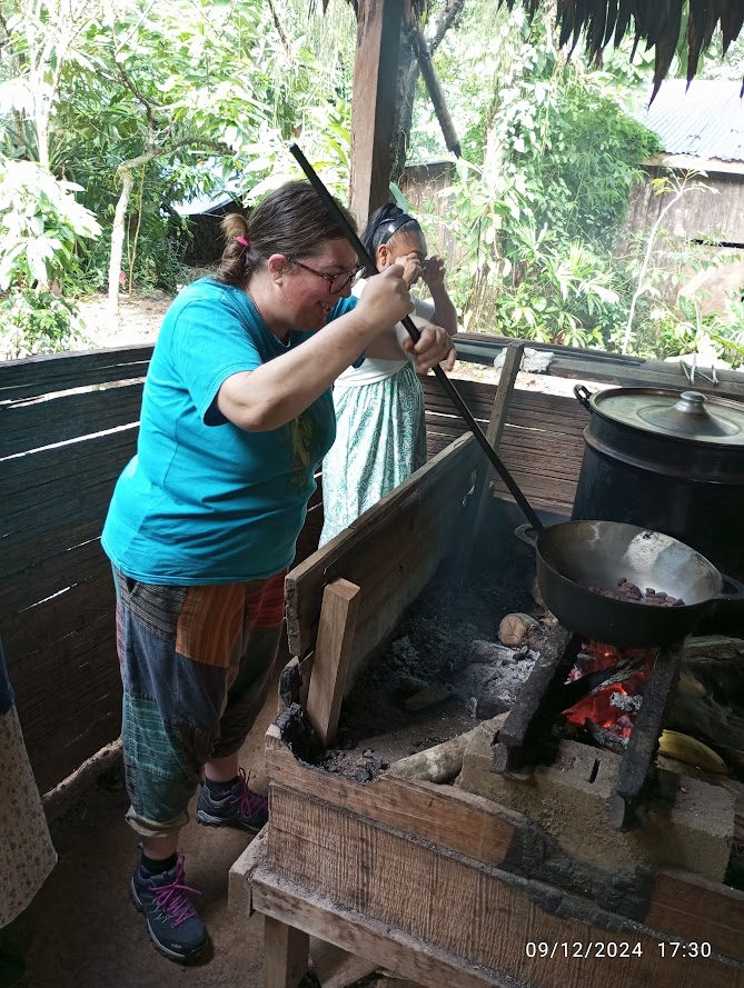 Romina tosta fave di cacao in Costa Rica usando una grande pentola su fuoco vivo in una cucina tradizionale all'aperto.