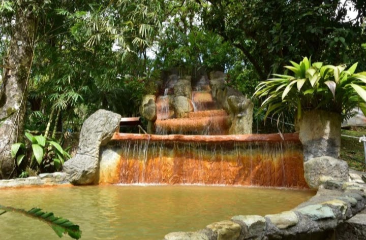 Relax e benessere ai piedi del vulcano Arenal in una piscina termale con cascate di pietra immerse nella giungla tropicale.