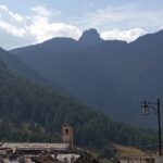 Chianale la perla della Val Varaita, borgo alpino con tetti in pietra e campanile tra montagne e boschi.