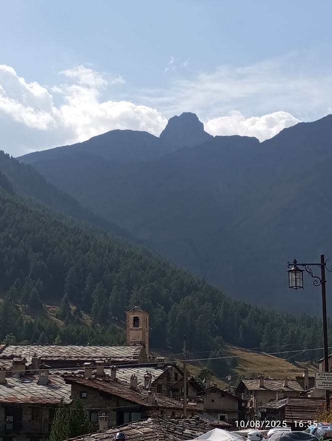 Chianale la perla della Val Varaita, borgo alpino con tetti in pietra e campanile tra montagne e boschi.