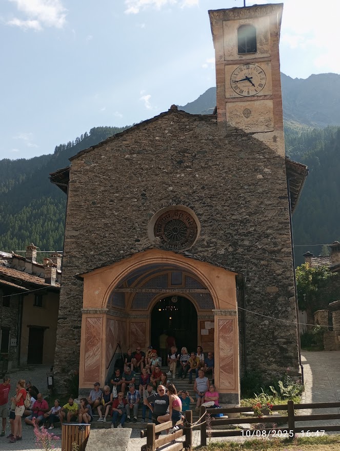 Chianale, la gemma della Val Varaita: facciata storica di chiesa con turisti seduti sulle scale.