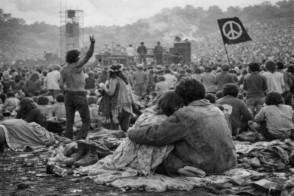 Immagine: Foto reportage in bianco e nero di un festival anni Sessanta: folla pacifica su un prato, musica, libertà, comunità e spirito di cambiamento collettivo. Woodstock 3 giorni di pace amore e musica
