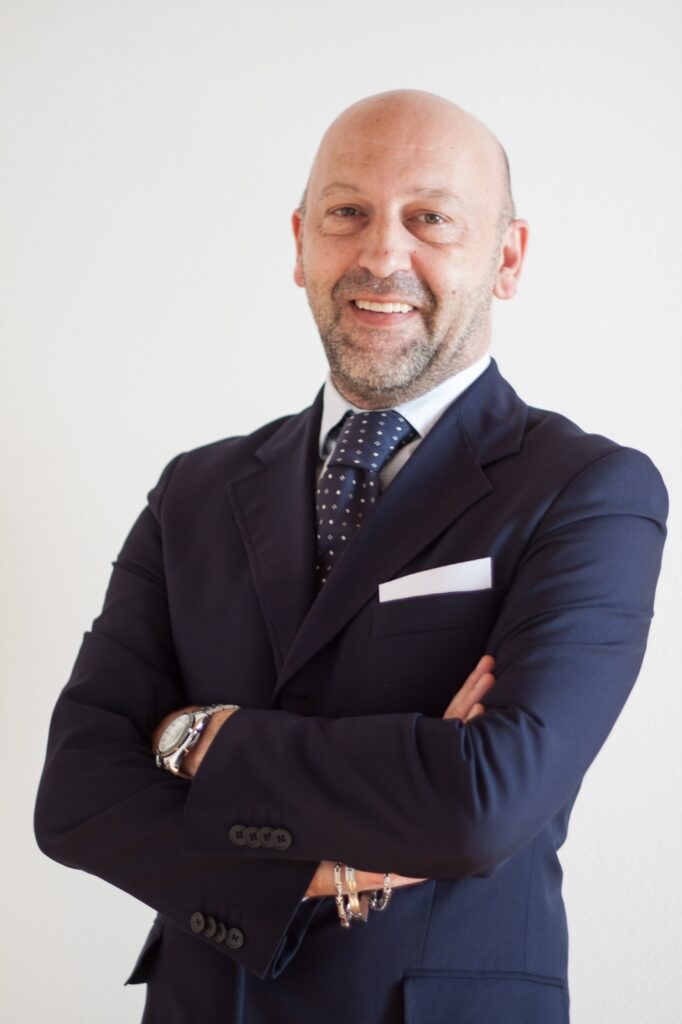 Fabrizio, life coach e programmatore, sorride con le braccia incrociate indossando un completo elegante blu scuro