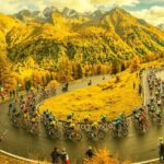 Il Tour de France in Italia: il gruppo sfreccia in una valle alpina gialla come la maglia del Tour, i tornanti sono gremiti di spettatori. Rappresenta appresenta la gloria e il sacrificio degli atleti.